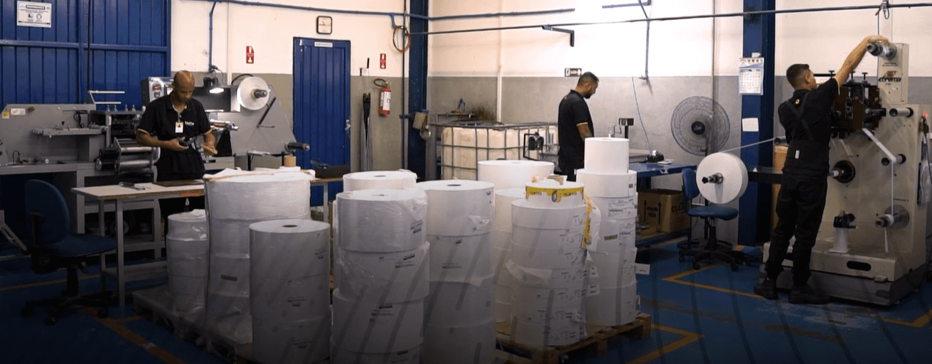 Fábrica com bobinas de papel e operador